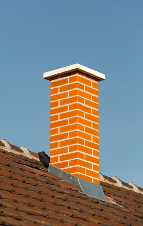 Chimney cap repair process in New Jersey with brick chimney under clear sky