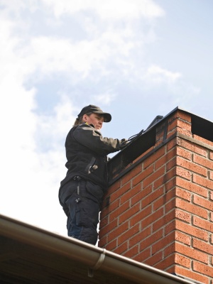 Chimney inspection and relining service takes place on a residential roof in New Jersey during clear weather Chimney inspection and relining service takes place on a residential roof in New Jersey during clear weather