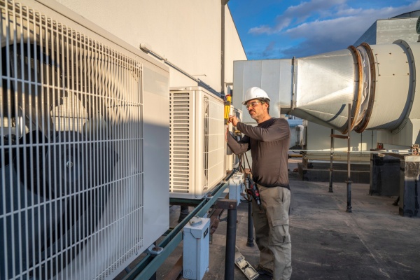Cleaning mini split air conditioning units on a rooftop during late afternoon sunlight Cleaning mini split air conditioning units on a rooftop during late afternoon sunlight