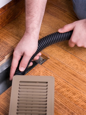 Homeowner cleaning dryer vent using vacuum hose to improve air flow and reduce fire risk in residential area Homeowner cleaning dryer vent using vacuum hose to improve air flow and reduce fire risk in residential area