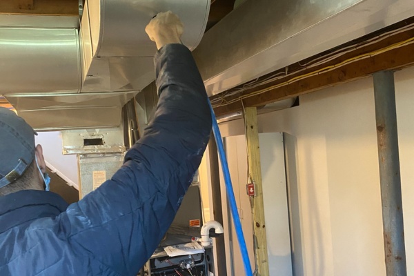 Service technician performing maintenance on booster fan in New Jersey residential space Service technician performing maintenance on booster fan in New Jersey residential space